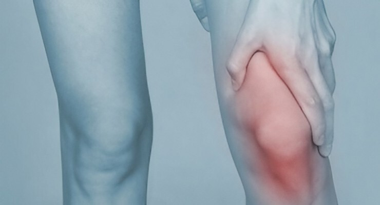 Persona sujetando la rodilla con zona resaltada en rojo por dolor