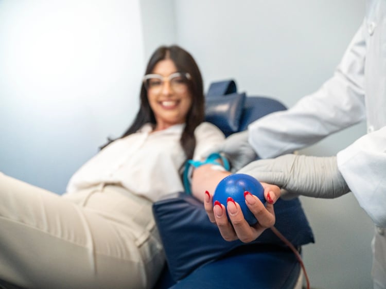 Woman realizes a blood donation while she is holding a plushy ball in clinic