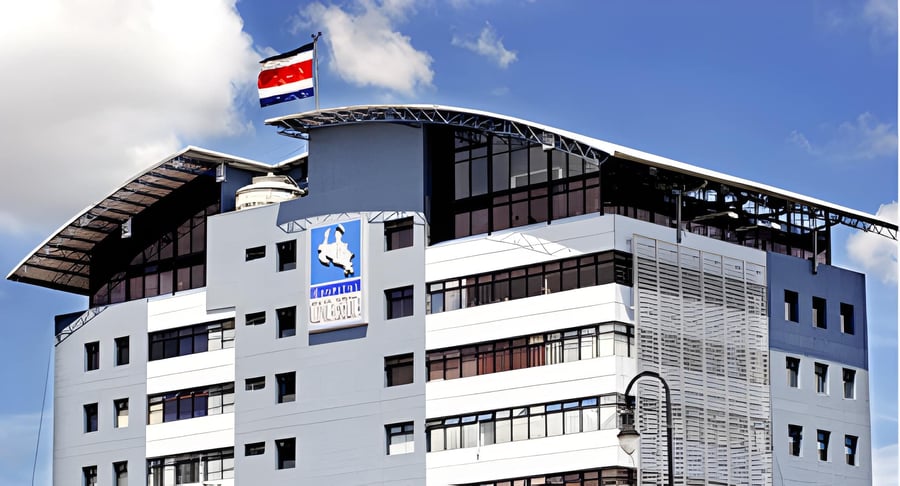 Edificio institucional de varios pisos con fachada moderna y bandera de Costa Rica en la parte superior.