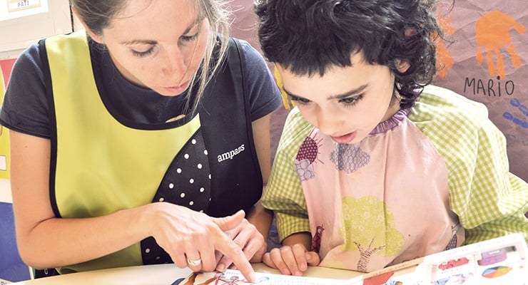Educadora acompañando a un niño mientras realizan una actividad educativa en una mesa