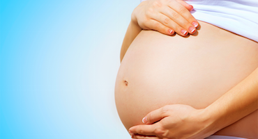 Vientre de mujer embarazada con manos apoyadas sobre el abdomen