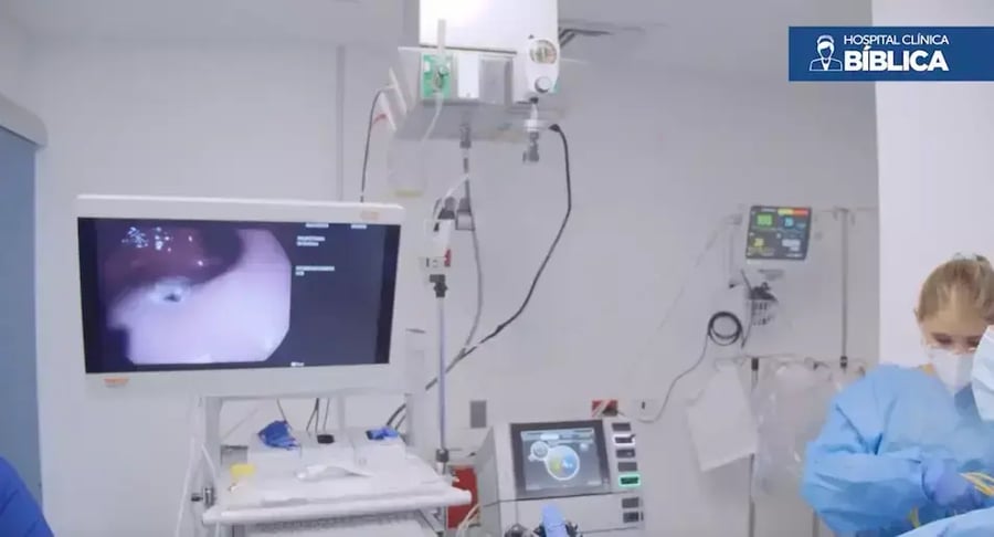Médica realizando procedimiento de endoscopia con monitoreo en pantalla en sala especializada