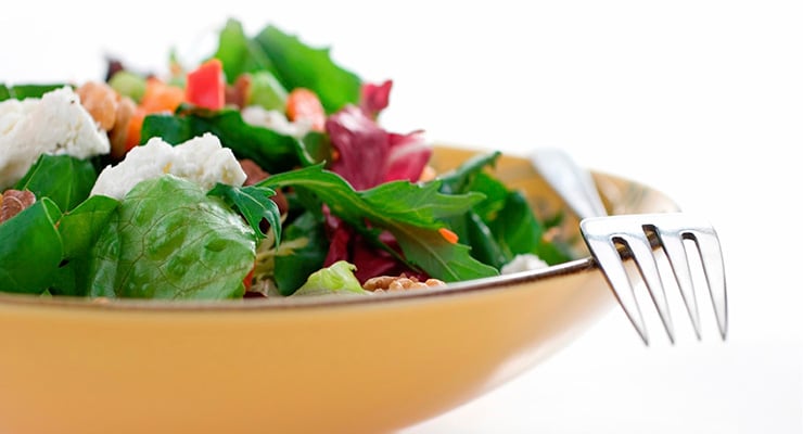 Plato de ensalada con hojas verdes, queso y vegetales frescos