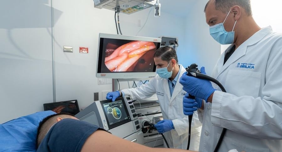 Especialistas en gastroenterología utilizando equipo de electrocirugía y endoscopia para detectar lesiones en el colon de un paciente.