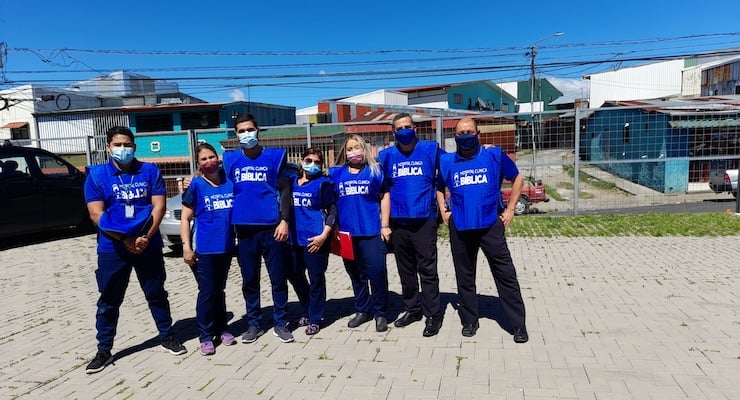 Colaboradores del Hospital Clínica Bíblica y el Ministerio Árbol de la Vida con chalecos azules y mascarillas durante una jornada de apoyo social.