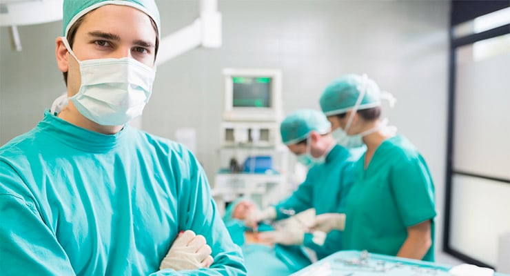 Equipo médico con vestimenta quirúrgica realizando un procedimiento en una sala de cirugía