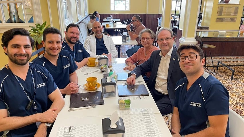 Grupo de profesionales del Hospital Clínica Bíblica reunidos alrededor de una mesa en un espacio interno.