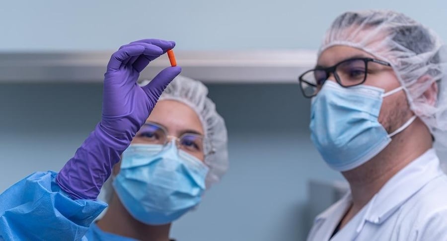 Dos profesionales de salud de Clínica Bíblica inspeccionando una cápsula personalizada bajo estrictos criterios de calidad.