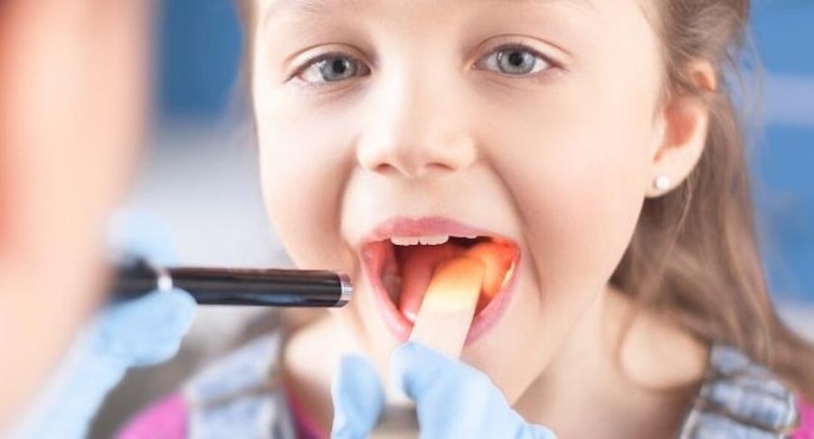 Evaluación de garganta en niña durante consulta médica pediátrica por amígdalas y adenoides