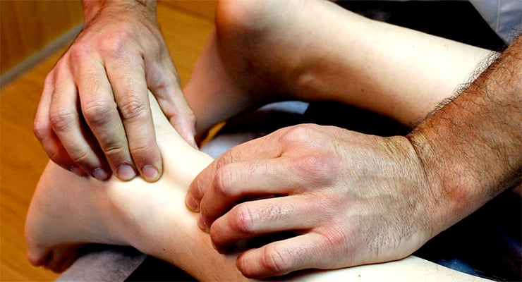 Profesional de salud evaluando el tendón de Aquiles en el pie de una persona