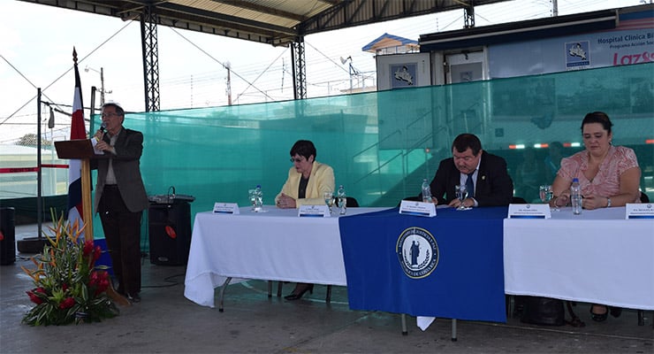 Acto público con mesa principal y orador de pie durante evento institucional en instalaciones del Hospital Clínica Bíblica.