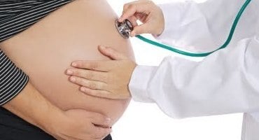 Médico realizando examen clínico a mujer embarazada durante control prenatal