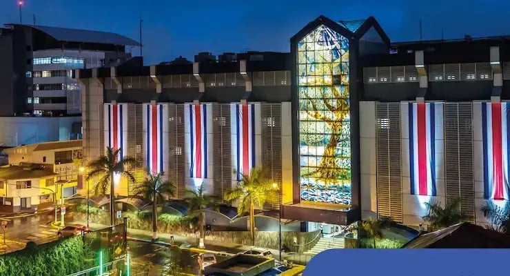 Fachada del Hospital Clínica Bíblica iluminada con banderas de Costa Rica