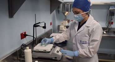 Farmacéutica utilizando equipo de laboratorio para preparar un medicamento