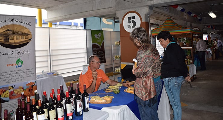 Personas visitando un puesto de degustación de productos artesanales durante una feria o exposición.
