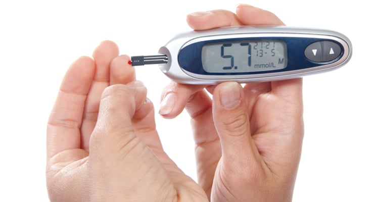 Persona sosteniendo un glucómetro mostrando el nivel de glucosa en pantalla