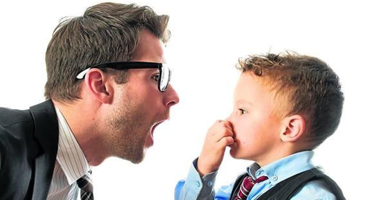 Hombre adulto hablando frente a un niño que se tapa la nariz