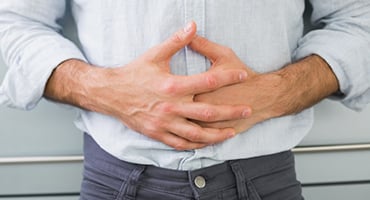 Hombre con las manos sobre el abdomen mostrando sensación de malestar o hambre