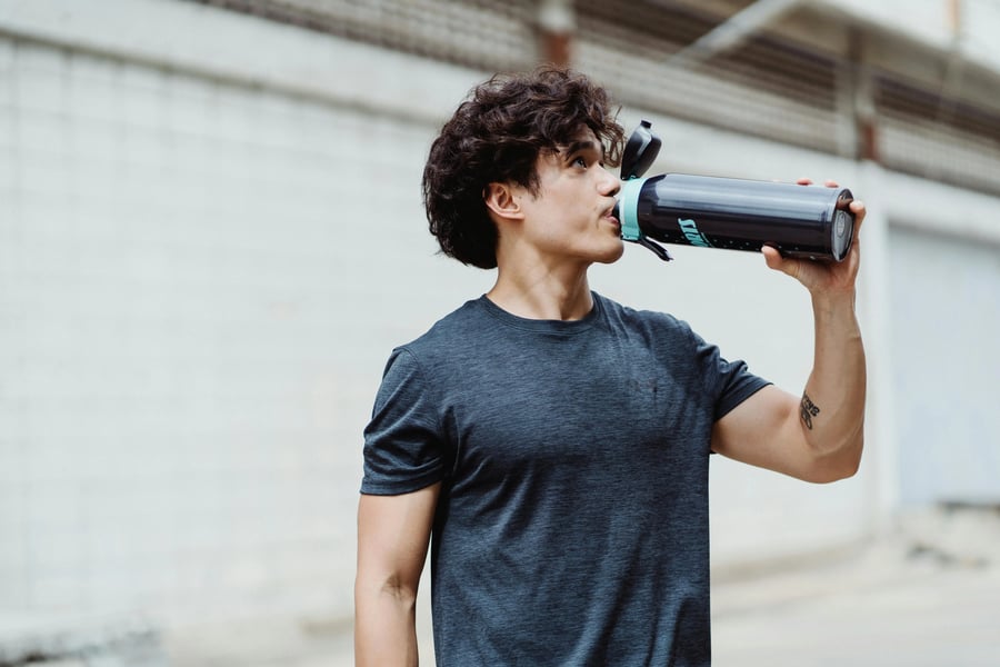 Hombre bebiendo agua de una botella durante actividad física