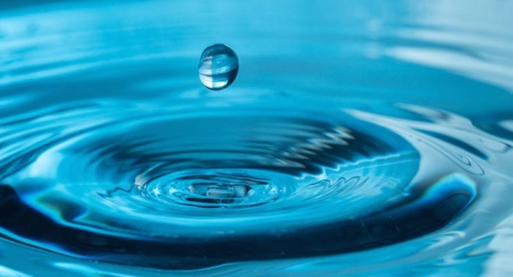 Primer plano de una gota de agua cayendo en una superficie azul, representando el cuidado del recurso hídrico en el Día Mundial del Agua.