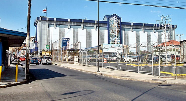 Vista exterior del Hospital Clínica Bíblica desde la calle, con vehículos y edificaciones alrededor.