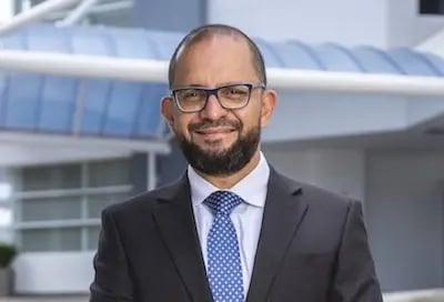 Hombre con traje y corbata posa frente a edificio corporativo moderno