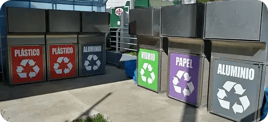 Estación de reciclaje con contenedores para plástico, aluminio, vidrio y papel.
