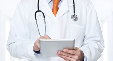 Médico de Clínica Bíblica utilizando una tableta digital para la gestión y prescripción automatizada de medicamentos.