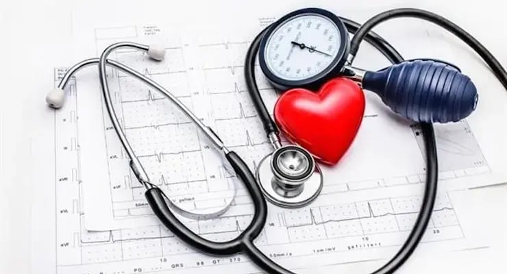 Instrumentos médicos sobre un electrocardiograma, incluyendo estetoscopio, baumanómetro y corazón rojo decorativo.