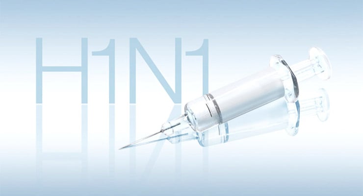 Jeringa médica sobre fondo claro con el texto H1N1 en segundo plano.