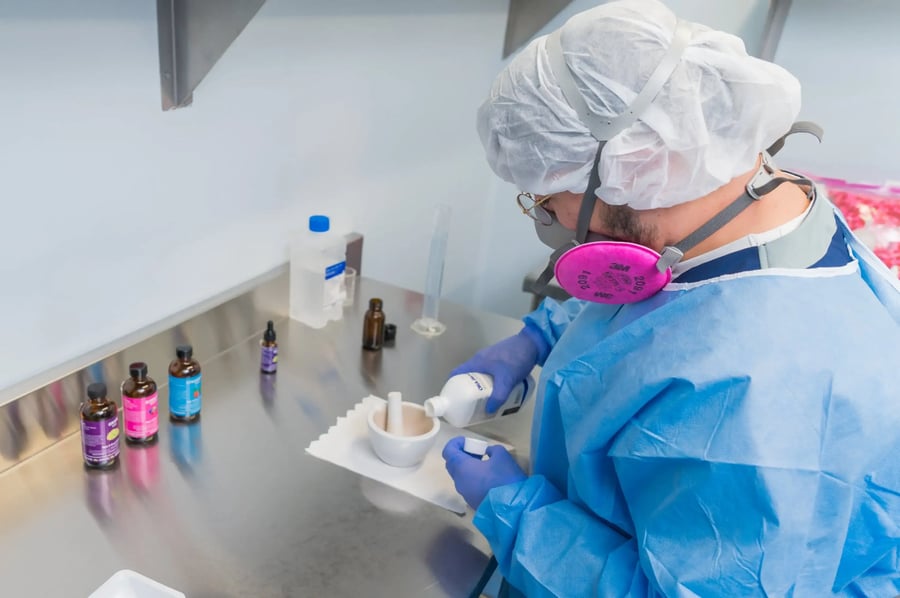 Personal de laboratorio preparando compuestos médicos con equipo de protección