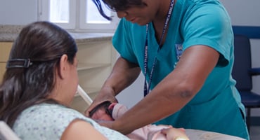 Madre amamantando a su bebé con apoyo de personal de salud en hospital
