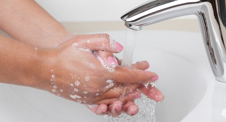 Manos lavándose con agua y jabón bajo un grifo