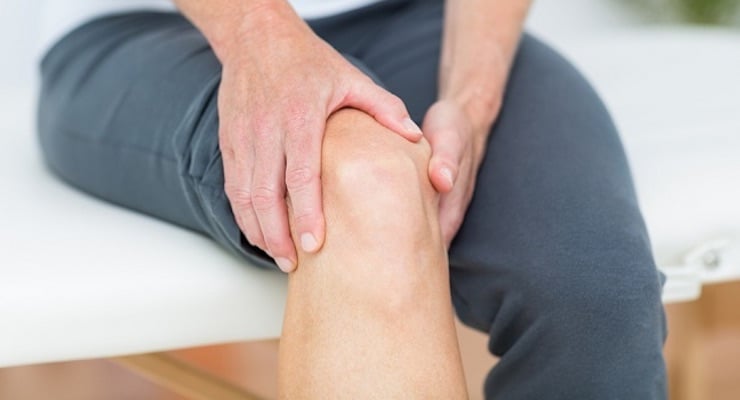 Persona sujetando su rodilla con ambas manos por problemas de circulación en las piernas