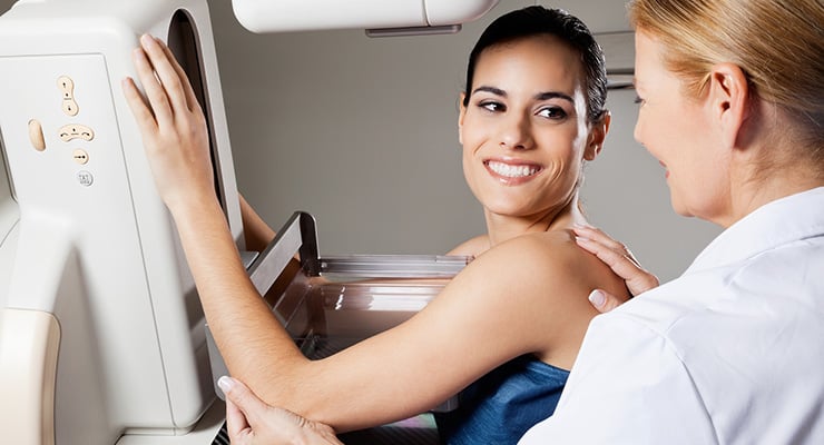 Mujer realizándose una mamografía asistida por personal médico en un equipo de diagnóstico por imágenes.