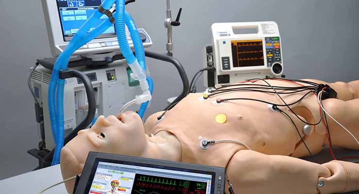 Maniquí de simulación médica conectado a equipos de monitoreo y soporte vital