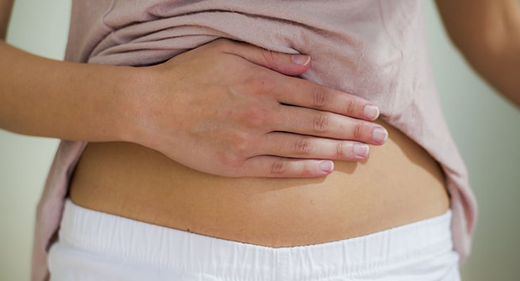 Mano apoyada sobre el abdomen de una persona a la altura del estómago