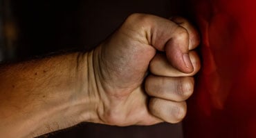 Puño cerrado frente a una superficie roja