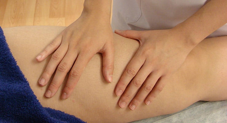 Manos aplicando presión sobre la pierna de una persona durante una terapia manual