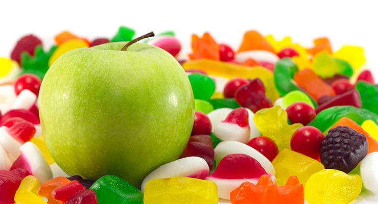 Manzana verde colocada sobre una variedad de dulces y gomitas de colores.