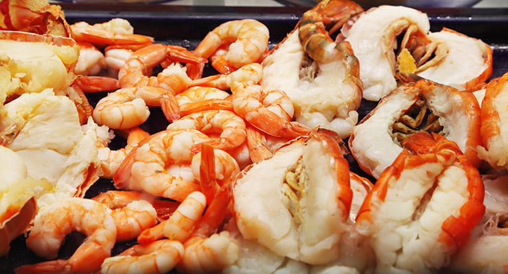 Mariscos cocidos como camarones y langosta dispuestos sobre una superficie