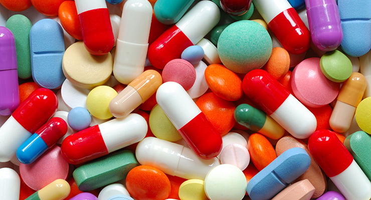 Pastillas y cápsulas de diferentes colores y tamaños agrupadas sobre una superficie