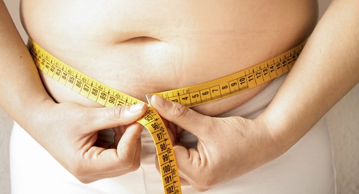 Persona midiendo la circunferencia del abdomen con una cinta métrica