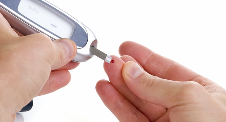Persona realizando una medición de glucosa en el dedo con un glucómetro