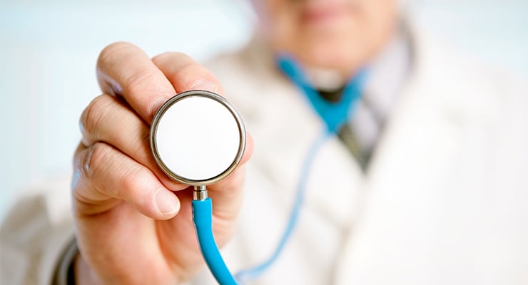 Profesional de la salud sosteniendo un estetoscopio frente a la cámara