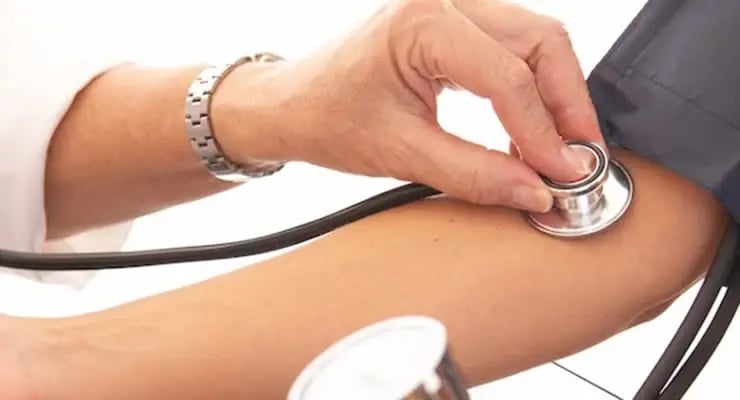 Profesional de salud midiendo la presión arterial en el brazo con estetoscopio y brazalete