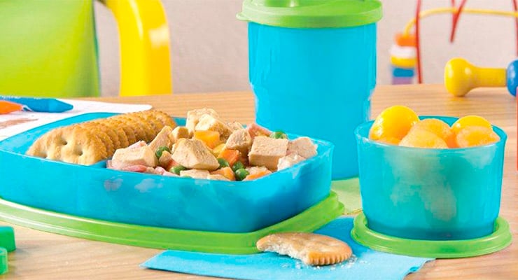 Lonchera infantil con sándwich, galletas, fruta y bebida sobre una mesa