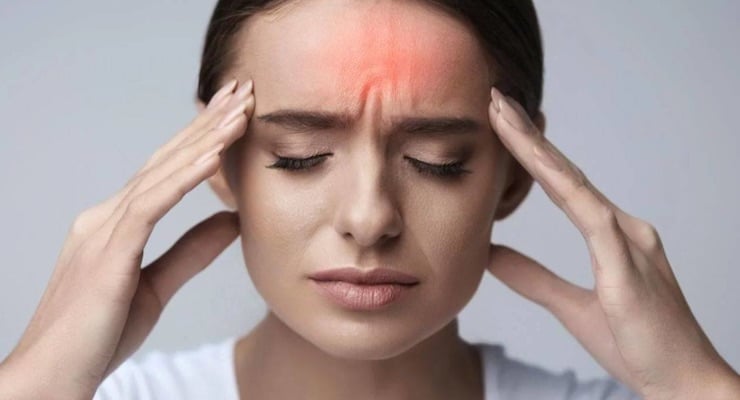 Mujer con dolor intenso en la frente sujetándose la cabeza por migraña