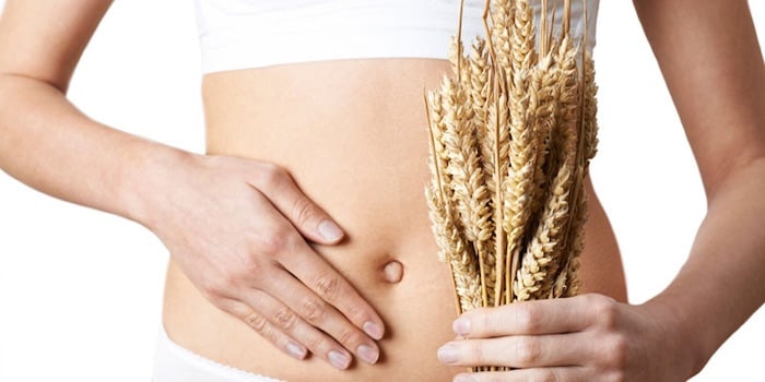 Abdomen de una persona sosteniendo espigas de trigo frente al cuerpo