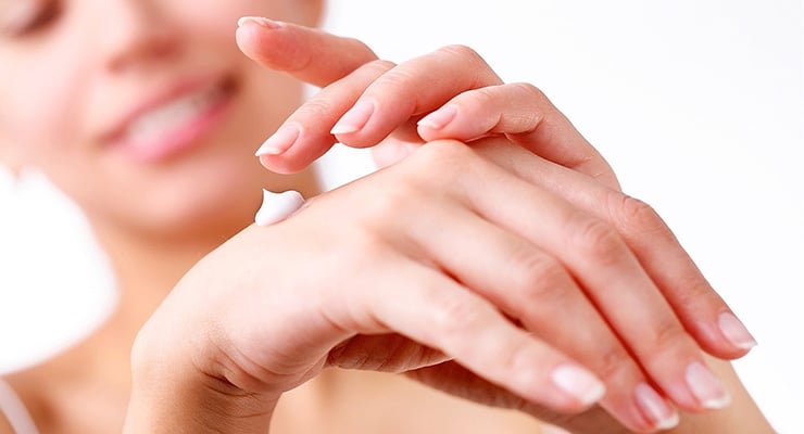 Mujer aplicando crema hidratante sobre el dorso de la mano